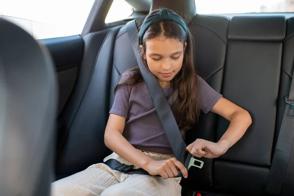 Schattig schoolmeisje bevestiging veiligheidsgordel terwijl zitten in de auto — Stockfoto