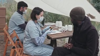 Çadırda yaşayan Afrikalı-Amerikalı mültecilere ilaç veren sağlık görevlilerinden oluşan orta ölçekli bir çekim.