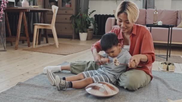 아시아 슬로우모가 귀여운 아들에게 거실에 코폰을 연주하는 모습을 — 비디오