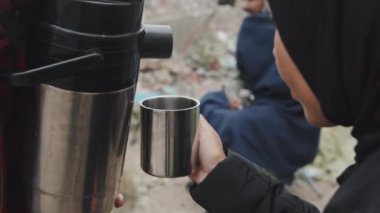 Termostan evsizlere kadar çay içmiş. Mülteci kampında diğer göçmenlerle yaşayan siyah ırk türbanlı bir kadın.