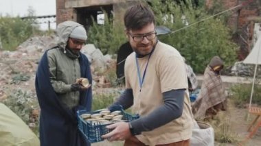 Erkek gönüllülerin mülteci kampındaki çadırlarda yaşayan çeşitli kişilere konserve yemek verirken çekilen fotoğrafı.