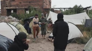 Askeri üniformalı sosyal görevli ve polis memurunun mülteci kampının çadırlarında gezerken çekilmiş bir fotoğrafı.