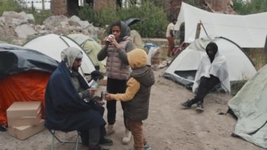 Diğer göçmenlerin yaşadığı fakir mülteci kampında metal bardaklardan su içen iki evsiz küçük Afro-Amerikan kızı.