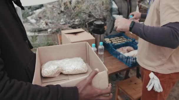 为帐篷城市生活条件差的难民或无家可归者提供食物和水的社会工作者或志愿者的中等密切关注 — 图库视频影像