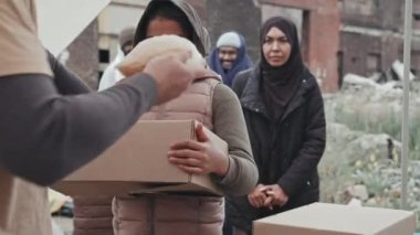 11 yaşındaki Afro-Amerikan bir kızın elinde karton bir kutuyla sosyal hizmet görevlilerinden yiyecek ve su aldığı orta boy bir fotoğraf. Bedava yemek kuyruğunda bekleyen diğer göçmenler