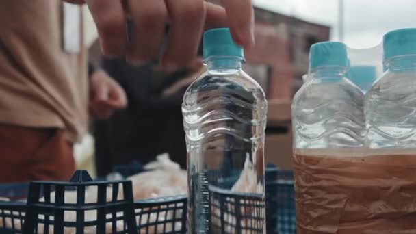 为生活在贫穷帐篷城市的非洲裔美国难民提供塑料瓶装水的不知名志愿者的慢镜头特写 — 图库视频影像