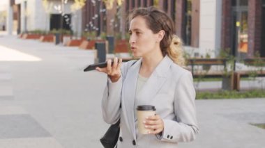 Kendine güvenen, şık takım elbiseli genç bir iş kadınının sesli mesaj kaydettiği ya da şehir merkezinde kahve alıp telefon aracılığıyla konuştuğu orta yavaş bir çekim.