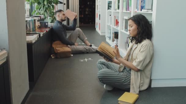 Modern Kütüphanede Yerde Otururken Kitap Okuyan Iki Genç Erkek Kadın — Stok video