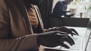 Orta ölçekli, genç, Afro-Amerikan girişimci iş adamlarının dizüstü bilgisayarda yazı yazarken modern ofiste finansal rapor yazmaları.