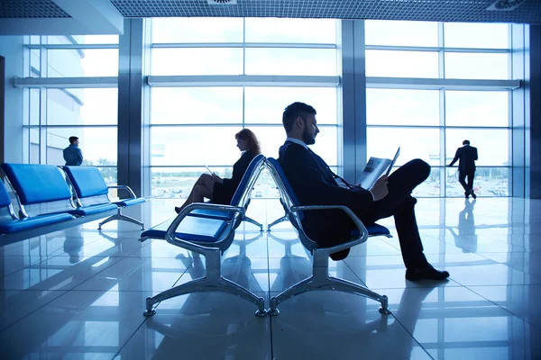 Zakelijke partners lezen op de luchthaven — Stockfoto