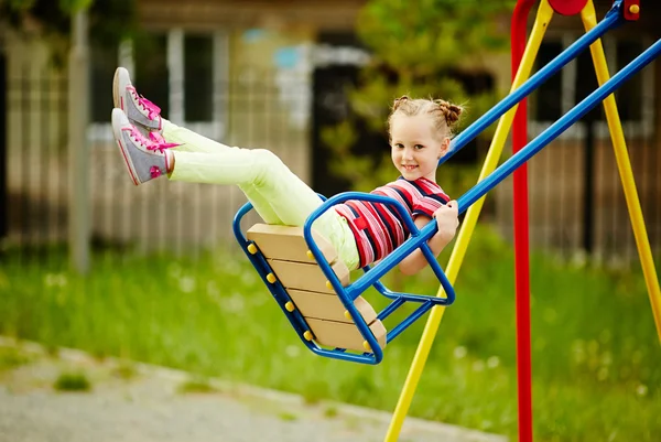 Girl swinging on playground — Stock Photo, Image