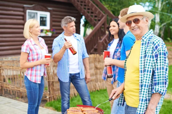 Senior man frying sausages — Stock Photo, Image