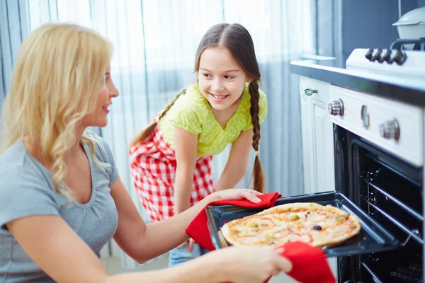 Kvinnan tar pizza ur ugnen — Stockfoto