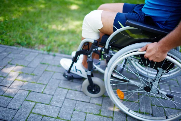 Hombre mano sobre rueda de silla de ruedas —  Fotos de Stock