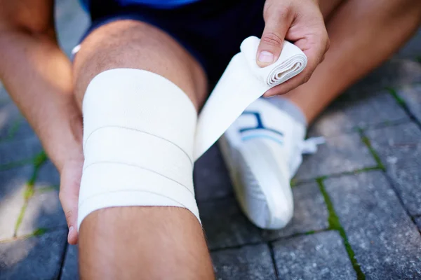 Man bandaging leg — Stock Photo, Image