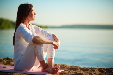 Woman sitting on sandy beach clipart