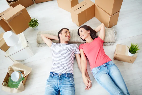 Pareja acostada en el suelo de una casa nueva — Foto de Stock