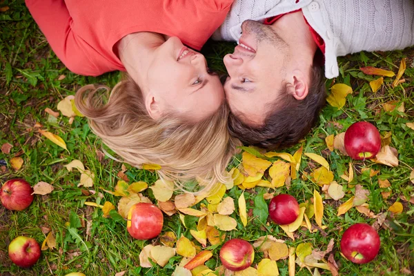 Couple  lying on ground with red apples — Stock Photo, Image