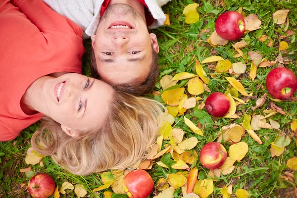 Пара лежить на землі з червоними яблуками — стокове фото