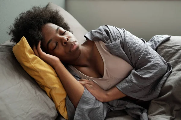 Ung avslappnad kvinna av afrikansk etnicitet sover i sängen — Stockfoto