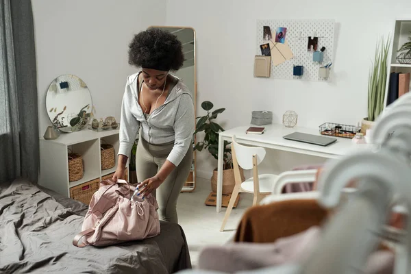 Jonge sportvrouw buigen over bed, terwijl het zetten van fles water in de zak — Stockfoto