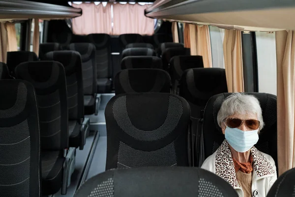 Зрелая женщина в защитной маске сидит на сидении внутри автобуса — стоковое фото
