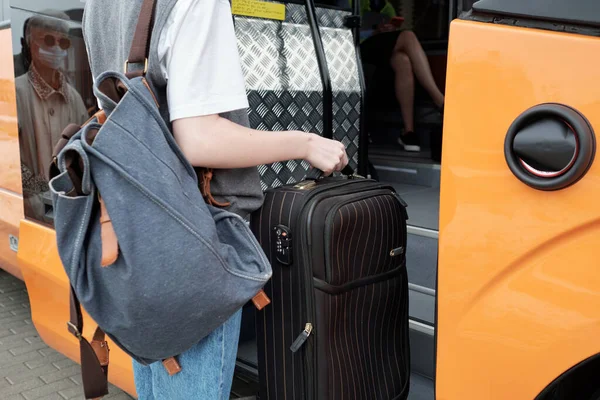 Young female with backpack and suitcase entering bus — Stock Photo, Image