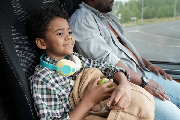 Feliz lindo niño con manzana y mochila sentado en el autobús — Foto de Stock