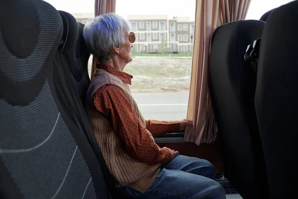 Mulher idosa em casualwear olhando pela janela enquanto sentada no ônibus — Fotografia de Stock