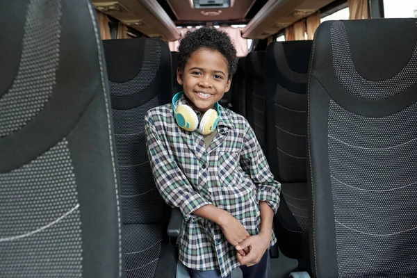 Счастливый милый маленький школьник в повседневной одежде стоит внутри автобуса — стоковое фото