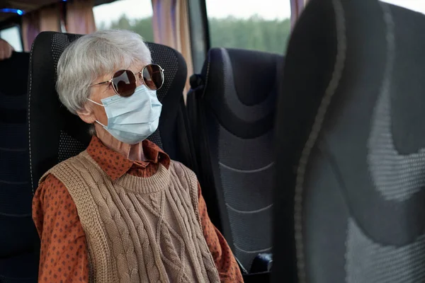 Старшая женщина в повседневной одежде, солнцезащитных очках и защитной маске — стоковое фото