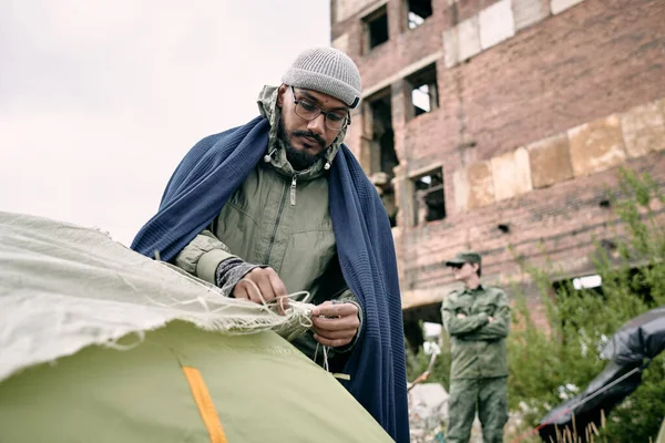 Hombre refugiado lanzando tienda contra medio edificio en ruinas —  Fotos de Stock