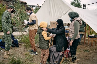 Koruyucu maskeli genç Müslüman kadın kızını giydiriyor.