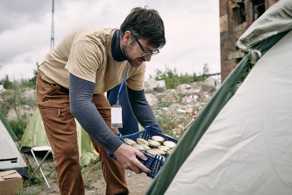 Férfi önkéntes dobozos ételhajlító sátorral — Stock Fotó
