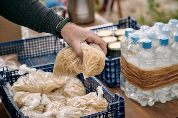 Рука волонтера берет мешки с макаронами для мигрантов — стоковое фото