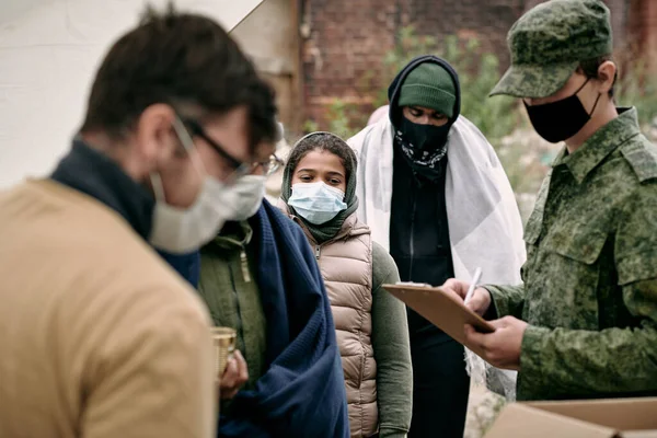 Группа мигрантов в защитных масках ждет пожертвования — стоковое фото