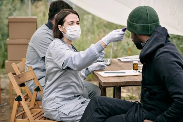 Doctor in beschermende masker meten lichaamstemperatuur van zieke man — Stockfoto