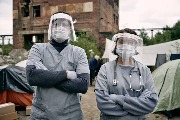 Два клинициста в защитной рабочей одежде стоят в лагере беженцев — стоковое фото