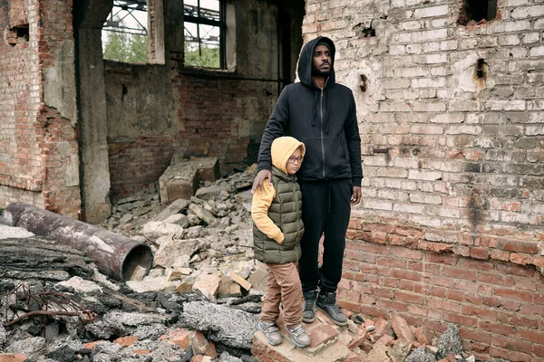 Mladý muž a holčička stojí vedle zničené budovy — Stock fotografie