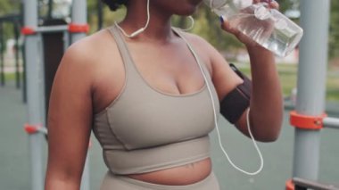 Açık hava sporları eğitiminde dinlenirken aktif giyimli Afrikalı Amerikalı bir kadının orta boy ağır çekimleri.