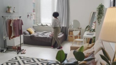 Sıkı spor giyim giymiş, spor antrenmanlarına gitmek için evden ayrılan, iri yarı, Afro-Amerikan bir kadının tam çekim yavaşlığı.