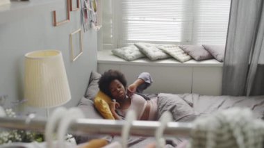İç çamaşırlı, Afro-Amerikan bir kadının parlak, modern bir dairede rahat bir yatakta uyanmasının yavaş çekimleri.