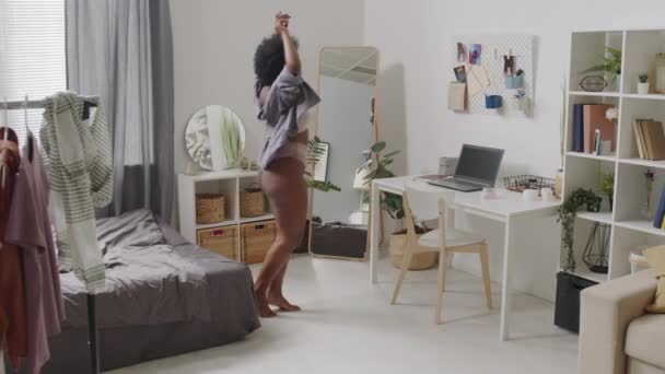 Full-length slow shot of young confident plus size Afro-americká žena v ležérní růžové spodní prádlo tanec v ložnici sám tráví čas se sebou