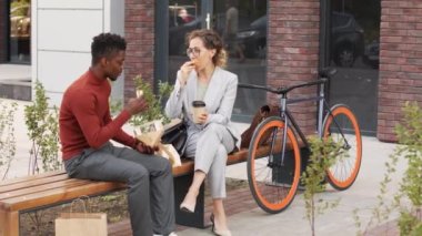 Yavaş çekimde zarif bir iş kadını Afro-Amerikalı erkek arkadaşıyla şehir merkezinde öğle yemeği yerken görülüyor.