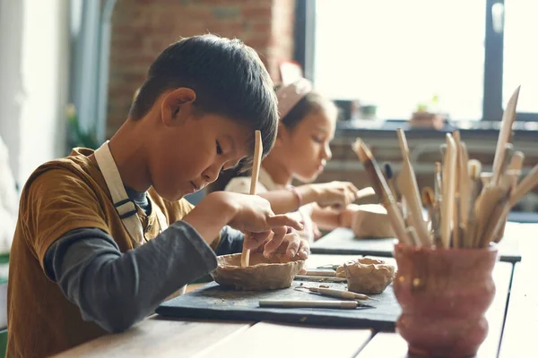 Хлопчик використовує дерев'яну палицю на класі кераміки — стокове фото