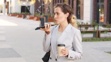 Kendine güvenen, şık takım elbiseli genç bir iş kadınının sesli mesaj kaydettiği ya da şehir merkezinde kahve alıp telefon aracılığıyla konuştuğu orta yavaş bir çekim.