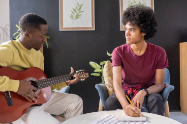 Müzik öğretmenine bakarken notlar alan zeki bir adam.