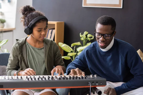 Cute biracial girl in headphones repeating after her music teacher — Stock Photo, Image
