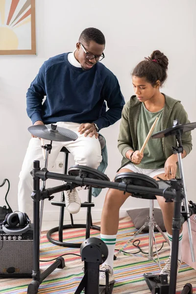 Young African man explaining biracial schoolgirl how to play drumset — Stock Photo, Image