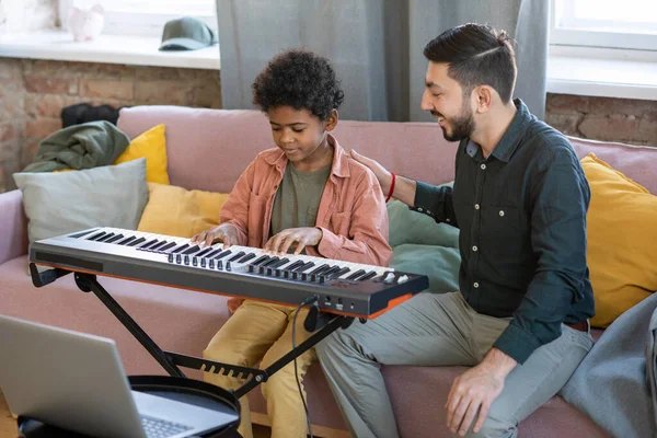 Young music teacher lauding his pupil playing piano keyboard — Stock Photo, Image